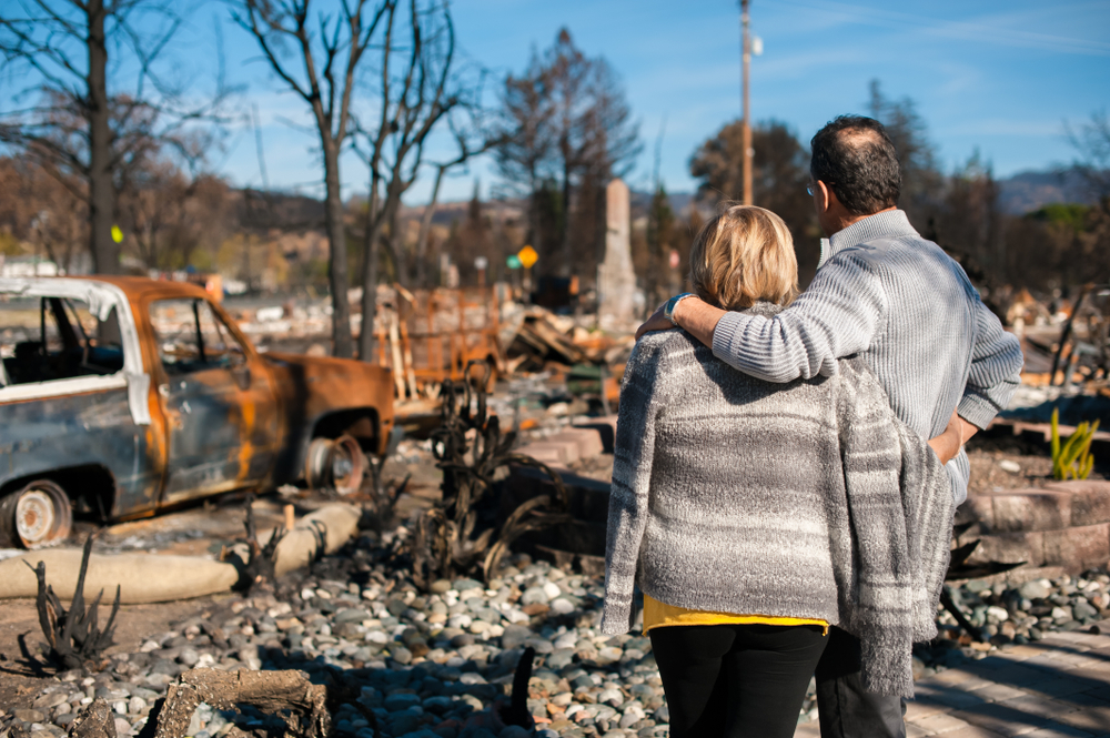 a man and woman looking at the aftermath of a disaster