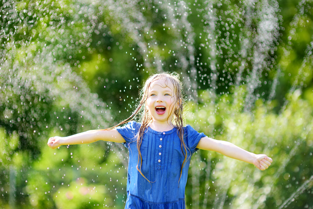 little girl running through a sprinkler