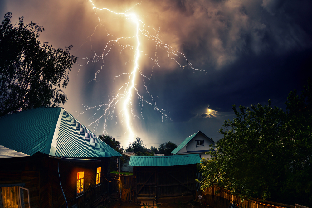 lightning striking behind a house at night