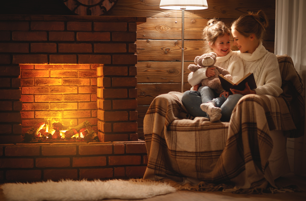 a mom and daughter sitting by a fire in their home