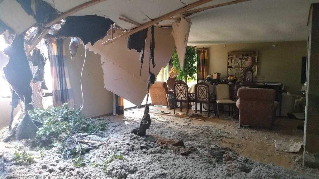 Severe storm damage with a collapsed ceiling and debris in the living room in Oconomowoc, WI