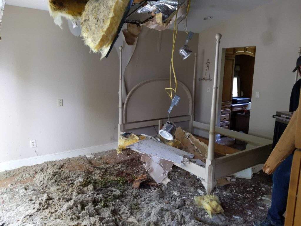 Bedroom ceiling collapse with insulation and debris after storm damage in Oconomowoc, WI.